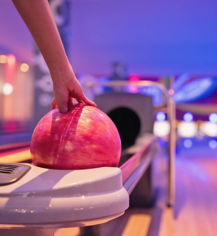 a woman placing her fingers inside of a bowling ball